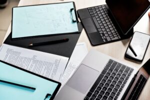 Desk with laoptop, tablet, clipboad, mobile phone pens and paper