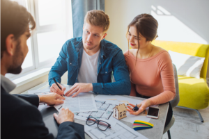 Young couple having a meeting with a professional signing a contract and holding house keys