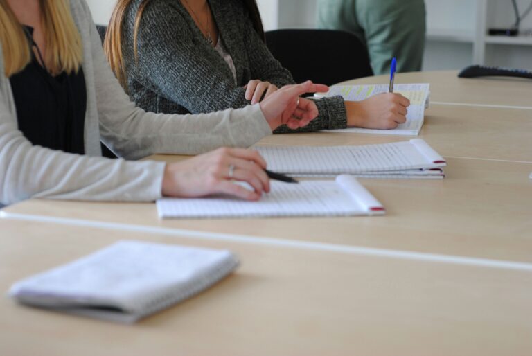 People sat at a desk in a meeting with one poinnting a finger