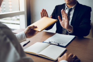Man holding up hands refusing to accept a brown envelope