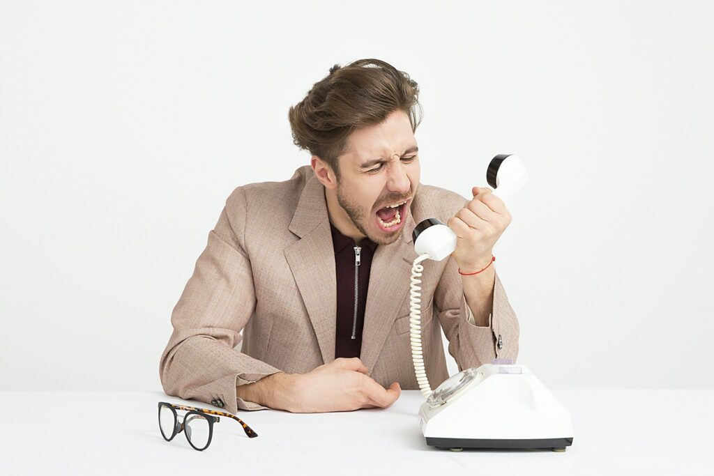 Man shouting frustratingly into a traditional telephone