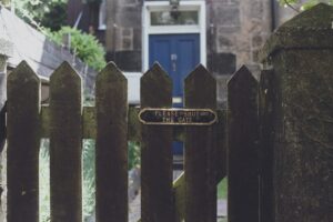 Wooden gate with brass sign showing please shut the gate - front door in blue