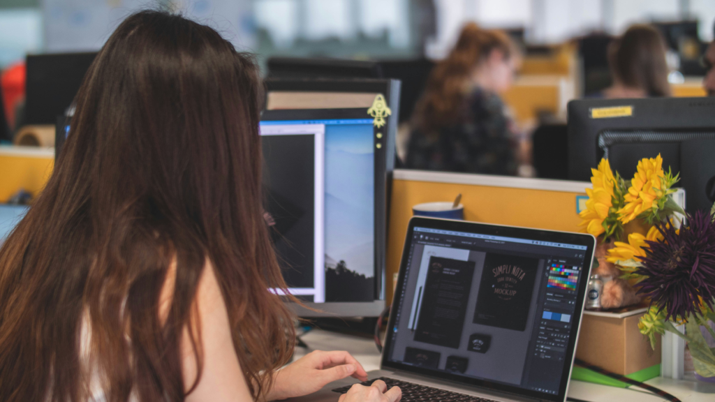Female with dark hair sitting at a desk on laptop working on a design project