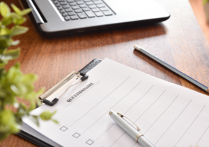 Clipboard on wooden desk holding a questionnaire with a pen and pencil