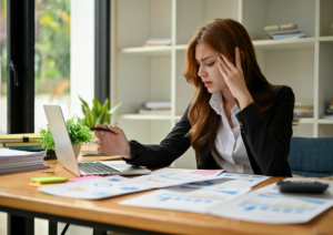 Woman in an office with papers on desk looking thoughtful
