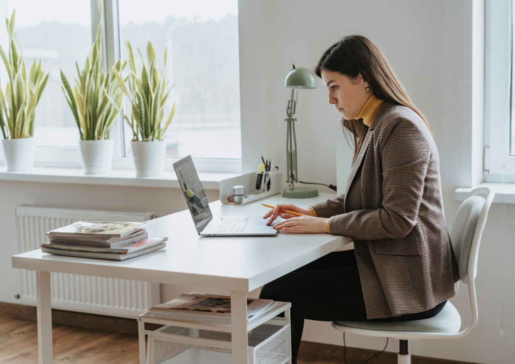 Woman sitting at a white desk working on laptop in contemporary office setting