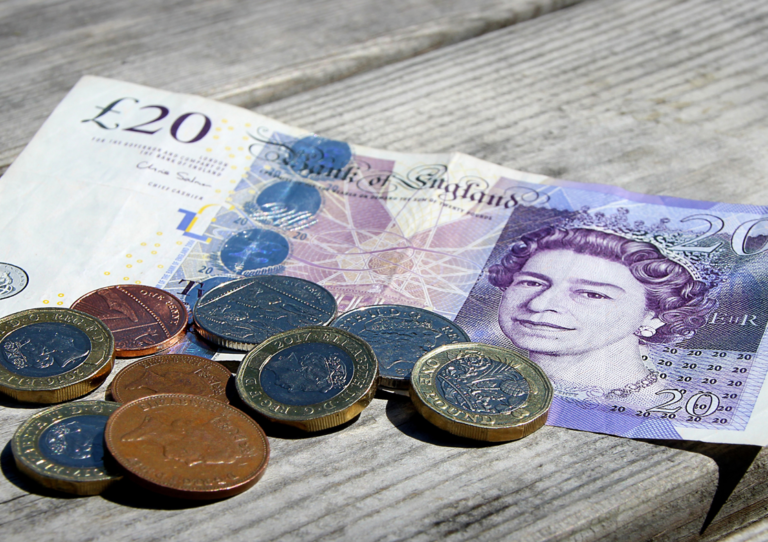 UK money scattered on a desk £20 note and loose change