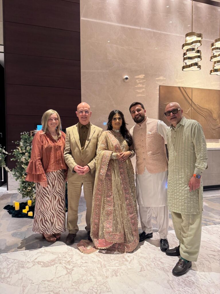 Group of people in wedding attire smiling into the camera