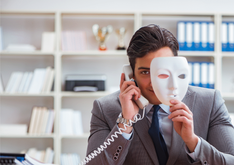Male wearing suit smirking into camera on phone whilst holding an opera mask NRA2025