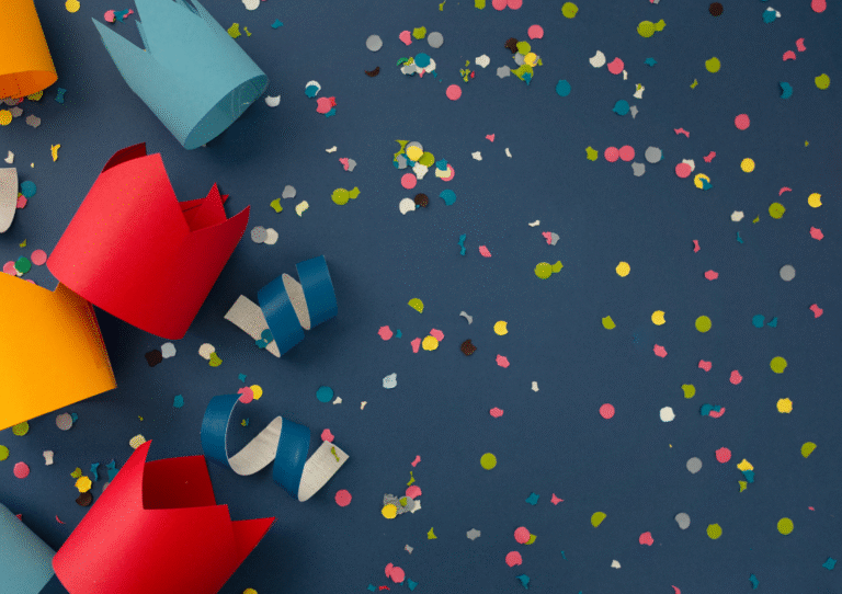 colourful party hats and confetti on a blue grey background