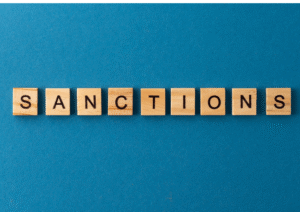 wooden cubes on a blue background that spell the words sanctions