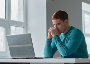 Man sitting at desk looking at computer concerned