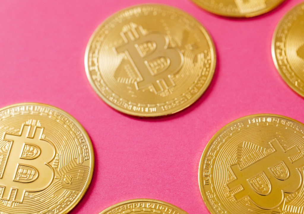 Graphic depicting gold bitcoin against a pink backdrop