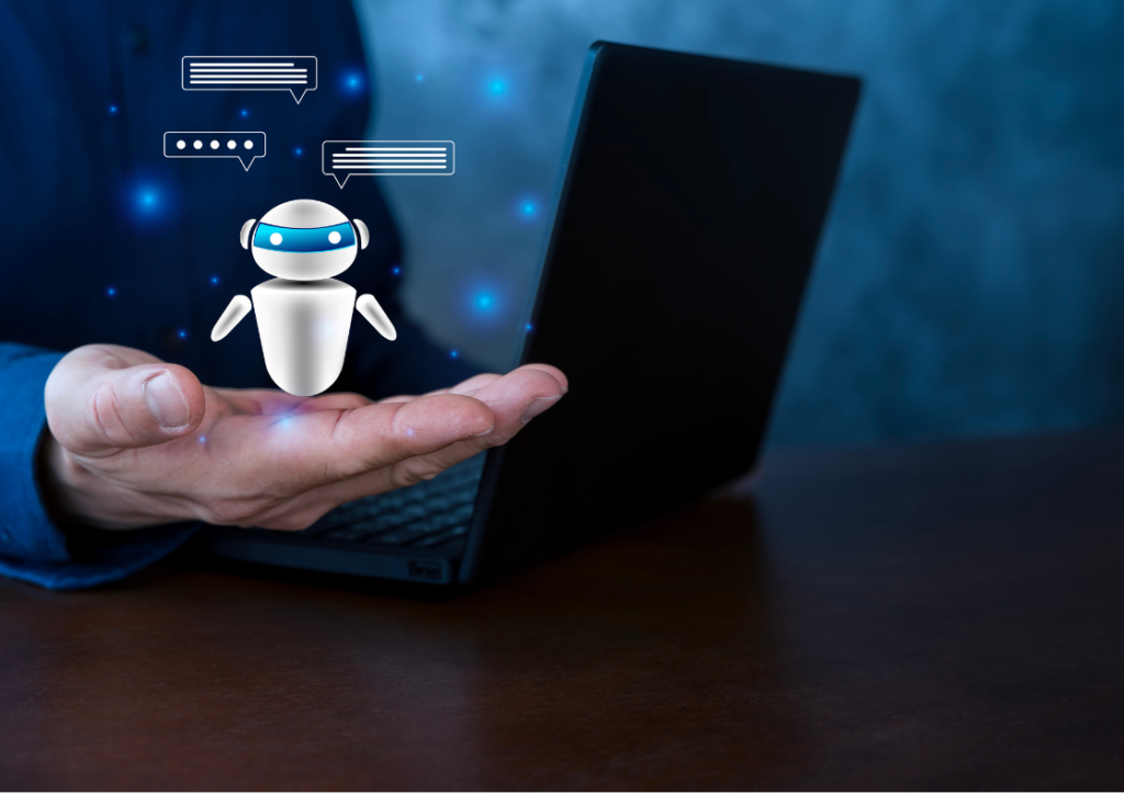 Hand holding a small robot against a backdrop of a laptop