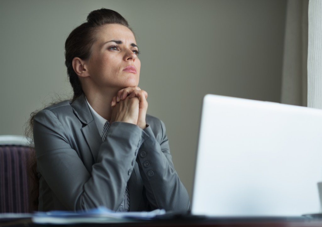 Female sitting at laptop with head on hands looking worried