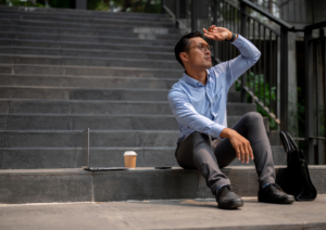 man sitting on steps looking into distance shielding his eyes