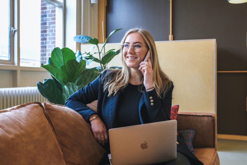 Woman in business attire sitting in modern office on phone smiling