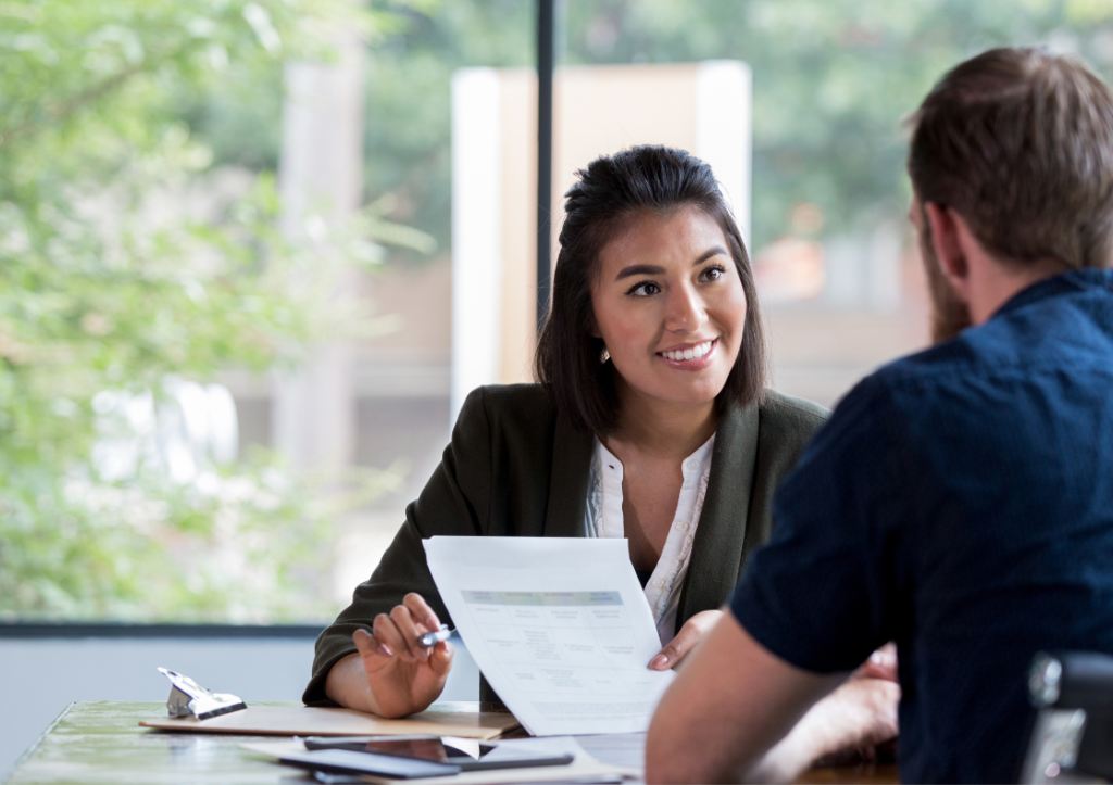 Man and woman having a business meeting with paperwork and smiling