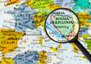 Map of the world with Bosnia and Herrtzagova underneath a magnifying glass