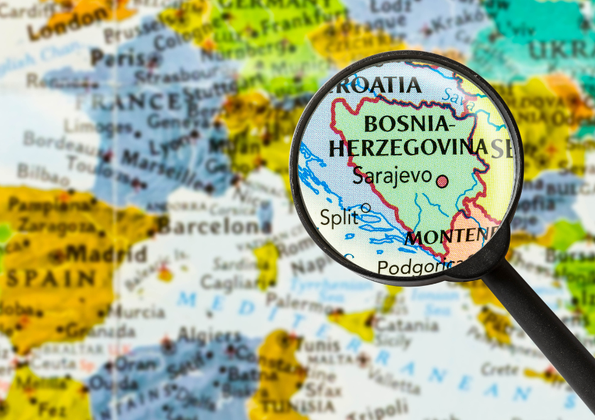 Map of the world with Bosnia and Herrtzagova underneath a magnifying glass